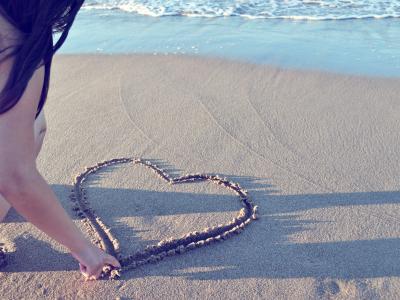 沙滩上刻画爱心的女孩